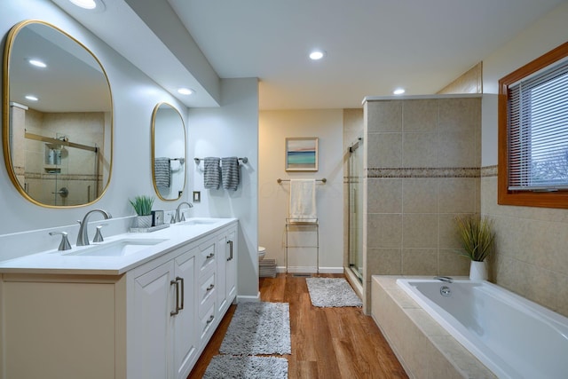 full bathroom featuring hardwood / wood-style flooring, plus walk in shower, vanity, and toilet