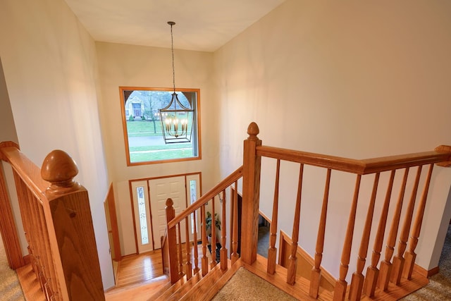 stairway with hardwood / wood-style flooring, a towering ceiling, and a notable chandelier