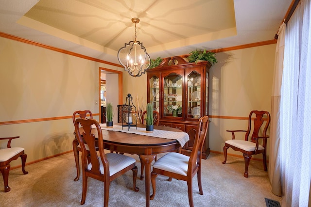 carpeted dining area featuring crown molding, a notable chandelier, and a tray ceiling