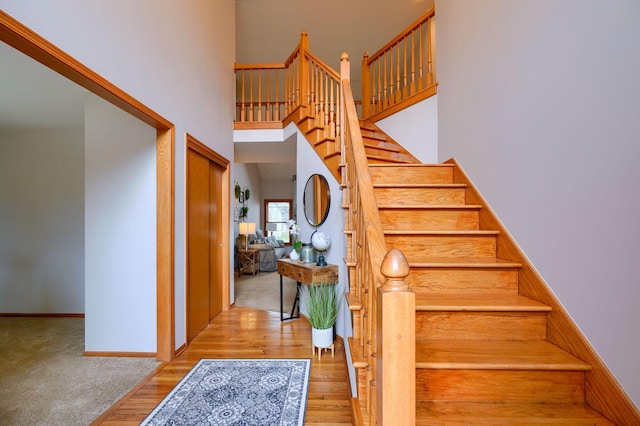 staircase with a high ceiling and wood-type flooring