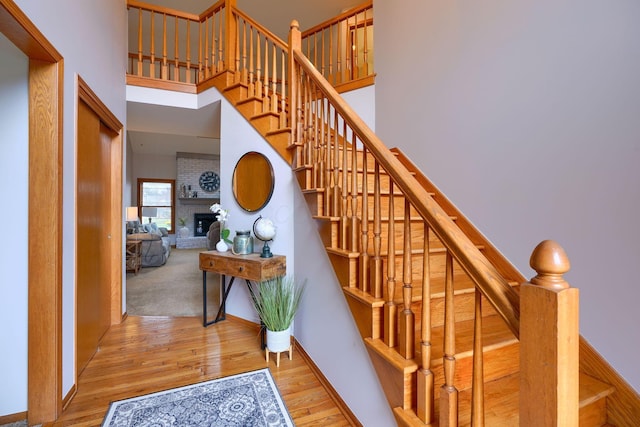 stairway featuring a towering ceiling, a fireplace, and hardwood / wood-style flooring