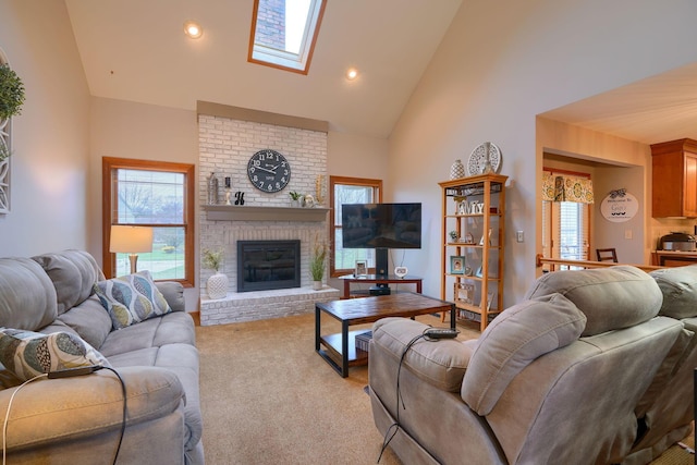 carpeted living room with a skylight, high vaulted ceiling, and a brick fireplace