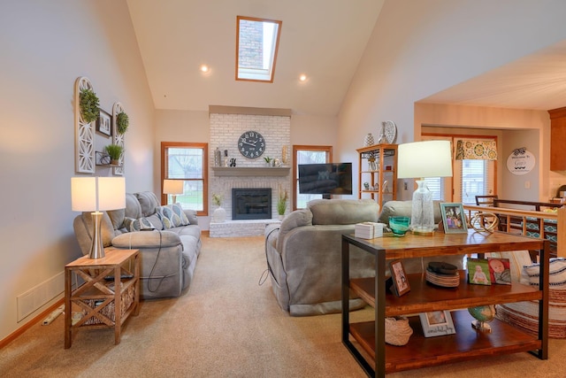 carpeted living room with a brick fireplace, a wealth of natural light, high vaulted ceiling, and a skylight