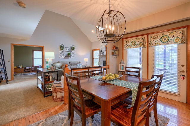 dining area featuring vaulted ceiling, a chandelier, and light wood-type flooring