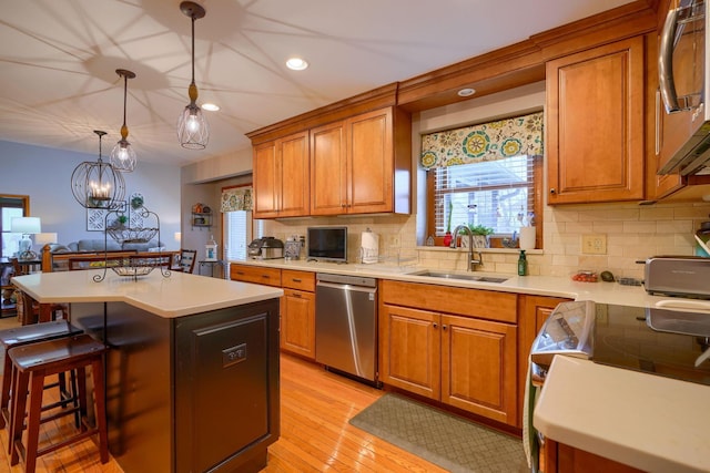 kitchen with pendant lighting, sink, a breakfast bar area, a center island, and stainless steel appliances