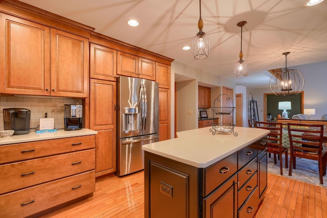 kitchen with stainless steel fridge, a kitchen island, pendant lighting, light hardwood / wood-style floors, and backsplash