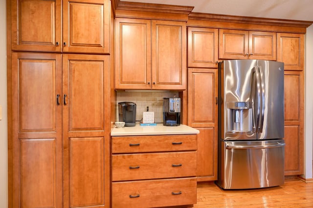 kitchen with tasteful backsplash, stainless steel refrigerator with ice dispenser, and light wood-type flooring