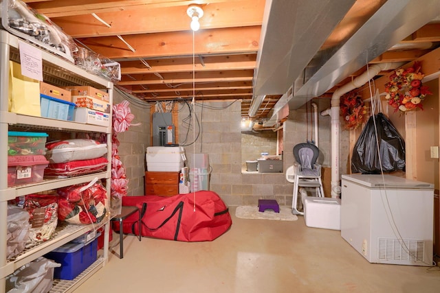 basement featuring electric panel and refrigerator