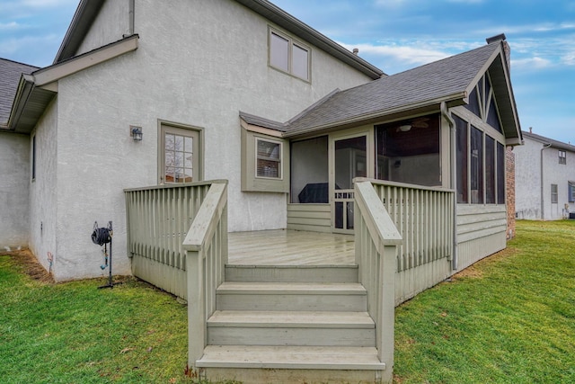 rear view of property featuring a wooden deck, a sunroom, and a yard