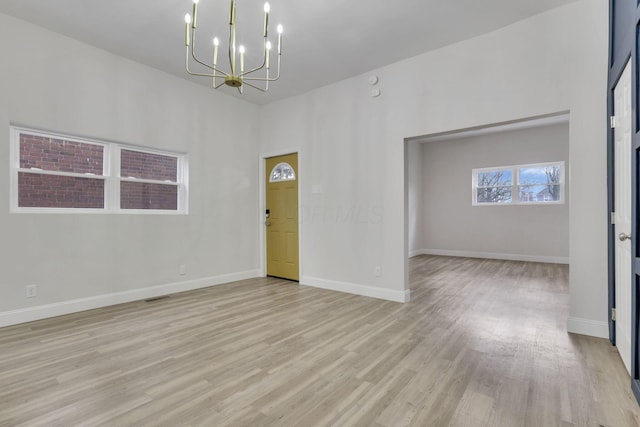 unfurnished room featuring a notable chandelier and light hardwood / wood-style floors