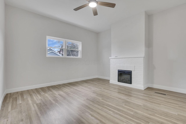 unfurnished living room with ceiling fan, a fireplace, and light hardwood / wood-style flooring