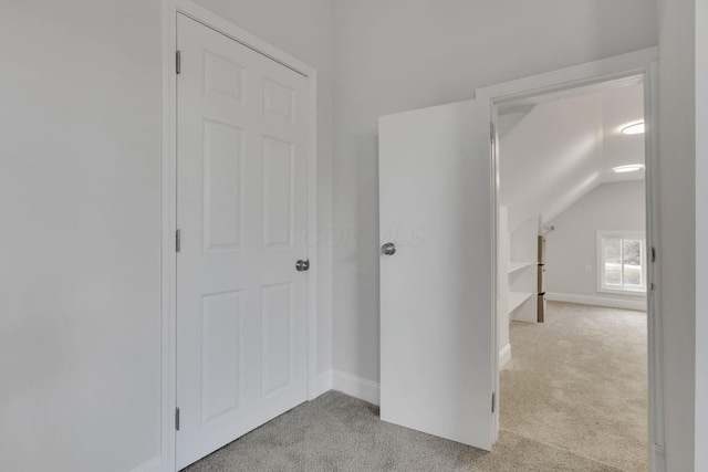 corridor with light carpet and vaulted ceiling