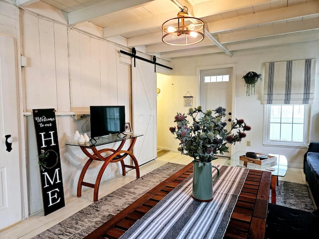 living room featuring wooden walls, a barn door, and beamed ceiling