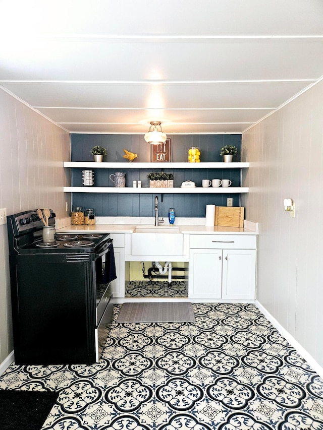 kitchen featuring sink, wood walls, white cabinets, and stainless steel electric range oven