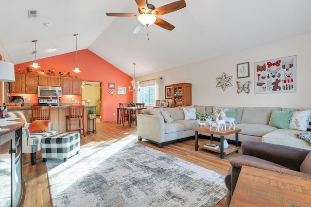 living room featuring ceiling fan, high vaulted ceiling, and light wood-type flooring