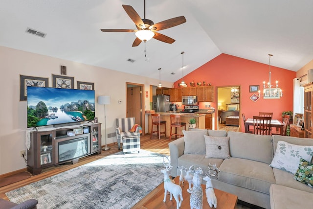 living room featuring lofted ceiling, ceiling fan with notable chandelier, and light wood-type flooring