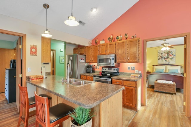 kitchen featuring appliances with stainless steel finishes, a breakfast bar, pendant lighting, sink, and kitchen peninsula