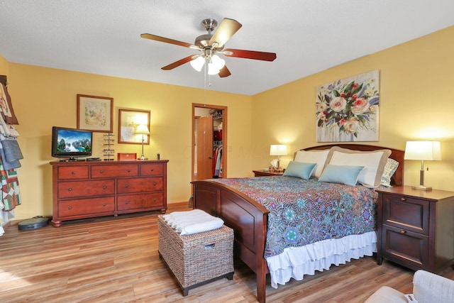 bedroom with a spacious closet, a closet, ceiling fan, and light wood-type flooring