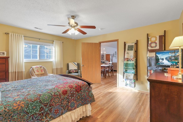 bedroom featuring ceiling fan, a textured ceiling, and light hardwood / wood-style flooring