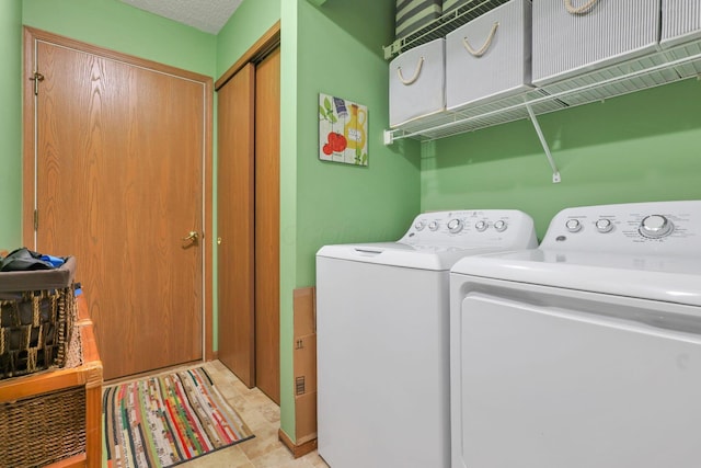 laundry area with washing machine and dryer and a textured ceiling