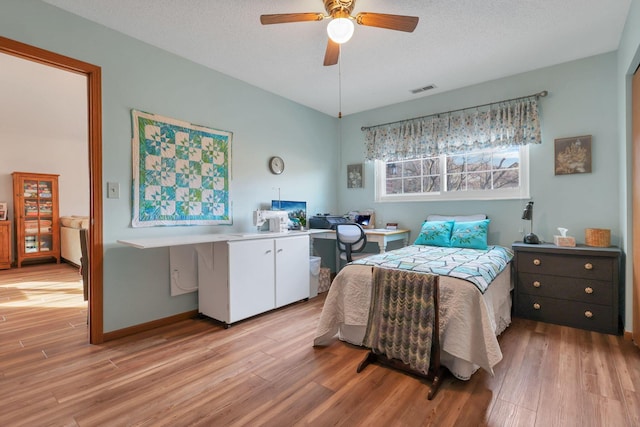 bedroom featuring ceiling fan, light hardwood / wood-style flooring, and a textured ceiling