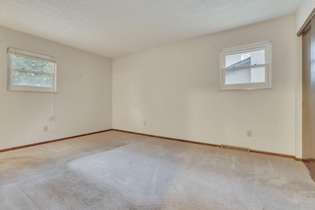 carpeted empty room with a textured ceiling