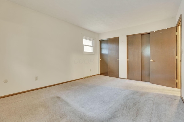 unfurnished bedroom with carpet floors and two closets