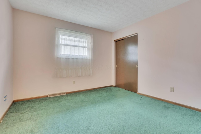 carpeted empty room with a textured ceiling