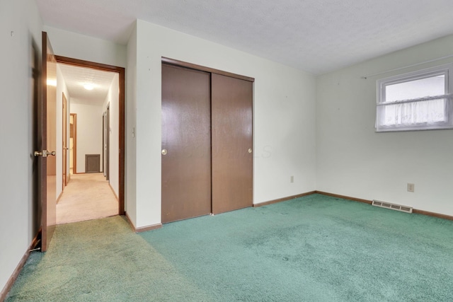 unfurnished bedroom with light carpet, a closet, and a textured ceiling