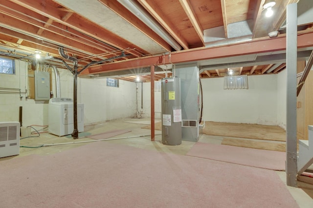 basement featuring washer and clothes dryer, electric panel, and water heater