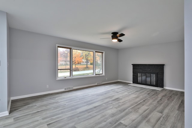 unfurnished living room with ceiling fan, light wood-type flooring, and a fireplace