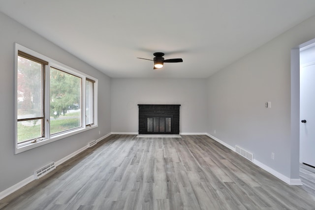 unfurnished living room featuring ceiling fan, a fireplace, and light hardwood / wood-style flooring