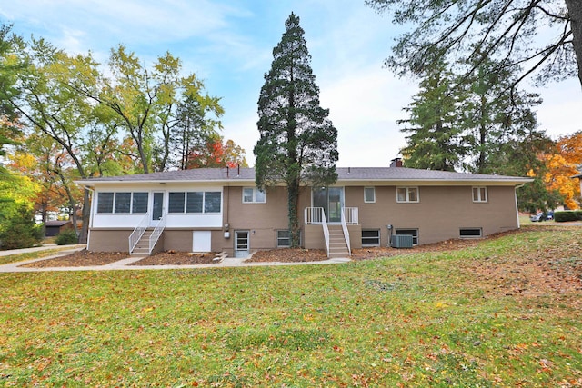 rear view of property featuring a lawn and central air condition unit