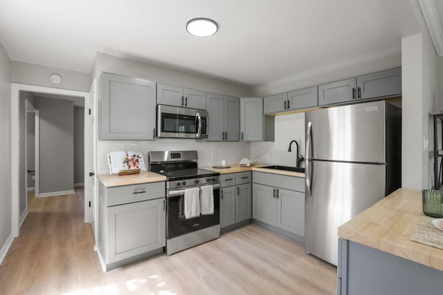 kitchen featuring gray cabinetry, sink, light hardwood / wood-style floors, and appliances with stainless steel finishes