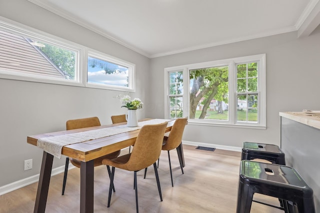 dining space featuring crown molding, a wealth of natural light, and light hardwood / wood-style floors