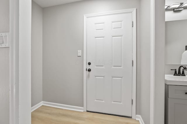 doorway to outside with light hardwood / wood-style floors and sink