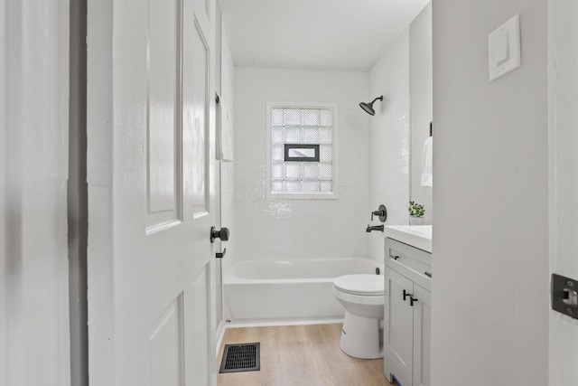 full bathroom with hardwood / wood-style flooring, vanity, tiled shower / bath combo, and toilet