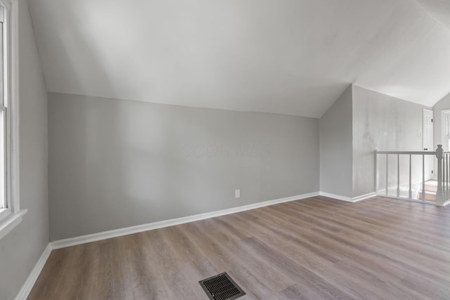 additional living space featuring vaulted ceiling and light hardwood / wood-style floors