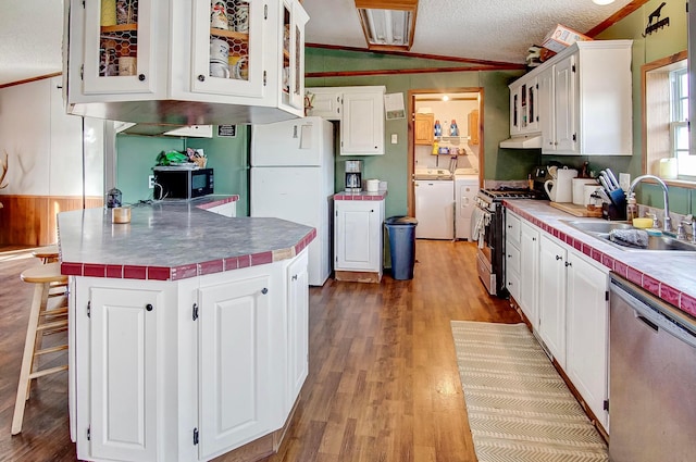 kitchen featuring washing machine and dryer, appliances with stainless steel finishes, sink, and white cabinets