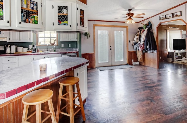 kitchen with ornamental molding, a breakfast bar, tile countertops, and white cabinets