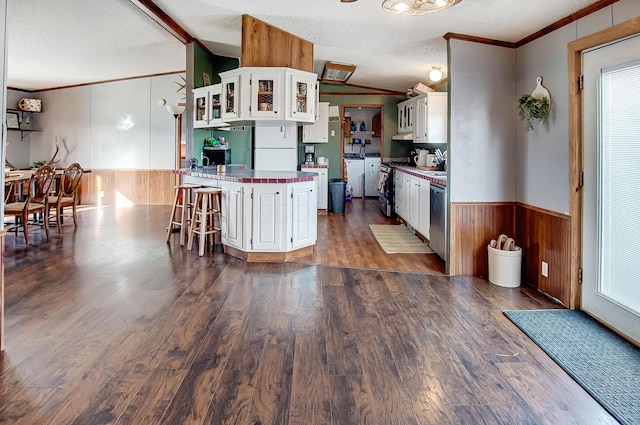 kitchen with vaulted ceiling, white cabinets, a kitchen breakfast bar, ornamental molding, and kitchen peninsula