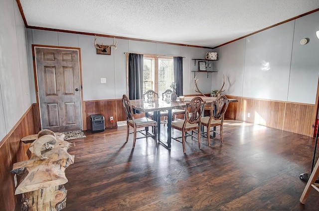 dining space with crown molding, dark wood-type flooring, a textured ceiling, and wood walls