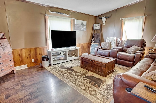 living room featuring wood-type flooring, ornamental molding, and wood walls