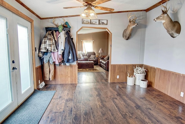 entryway featuring wooden walls, ceiling fan, crown molding, dark wood-type flooring, and french doors