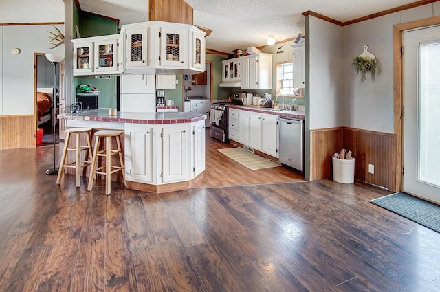 kitchen featuring appliances with stainless steel finishes, white cabinets, a kitchen bar, kitchen peninsula, and a textured ceiling