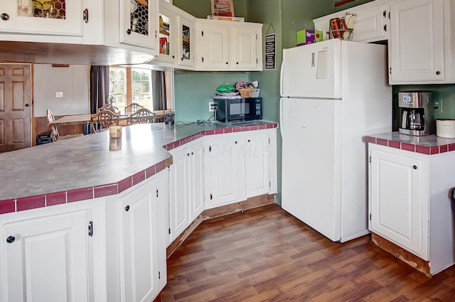 kitchen featuring hardwood / wood-style flooring, tile counters, white cabinets, and white refrigerator