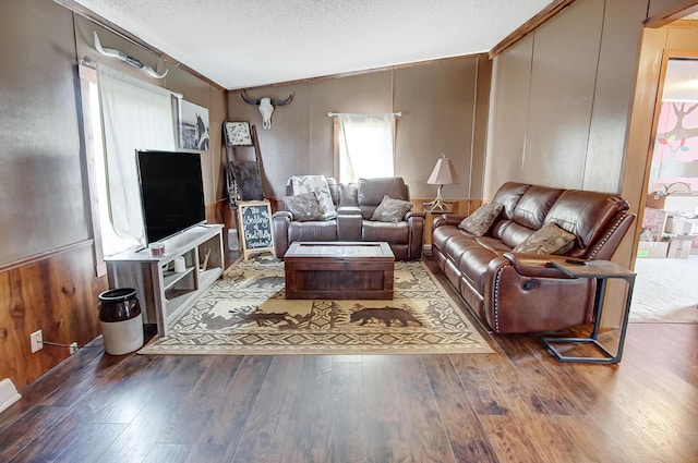 living room with hardwood / wood-style flooring, vaulted ceiling, wooden walls, and a textured ceiling