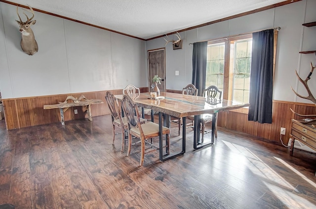 dining area featuring crown molding, dark hardwood / wood-style floors, a textured ceiling, and wood walls