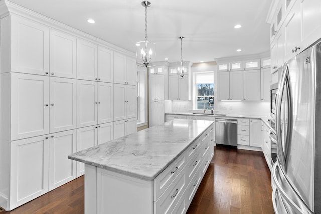 kitchen featuring pendant lighting, sink, stainless steel appliances, white cabinets, and a kitchen island