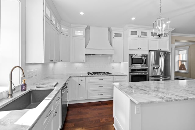 kitchen featuring white cabinetry, sink, stainless steel appliances, crown molding, and custom range hood